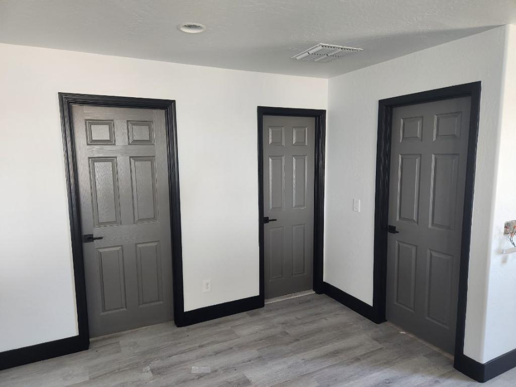 Three gray interior doors with black trim and baseboards