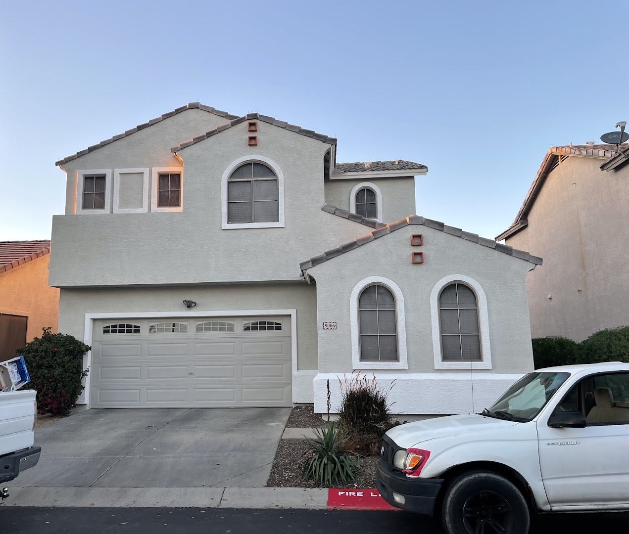 Two-story beige stucco home with arched windows and a two-car garage